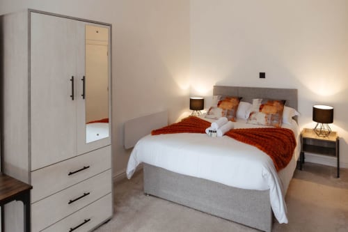 Modern bedroom at The Spacious Suite by JS Apartments in Blackburn with double bed, wardrobe, and warm lighting