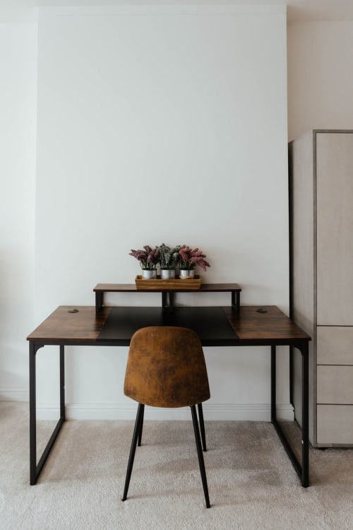 Modern work desk with brown chair in JS Apartments Blackburn suite, featuring potted plants and minimalist design