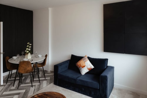 Modern spacious suite at JS Apartments, Blackburn, featuring navy sofa, dining table with chairs, and contemporary