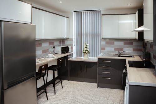 Modern kitchen in The Family Flat by JS Apartments, Blackburn, with white and dark cabinetry, stainless steel appliances, and