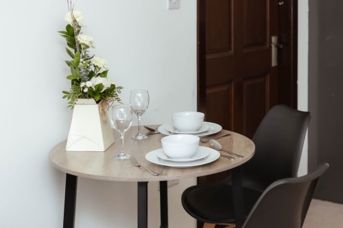 Elegant dining table set for two at JS Apartments Blackburn with white crockery, wine glasses and fresh flowers