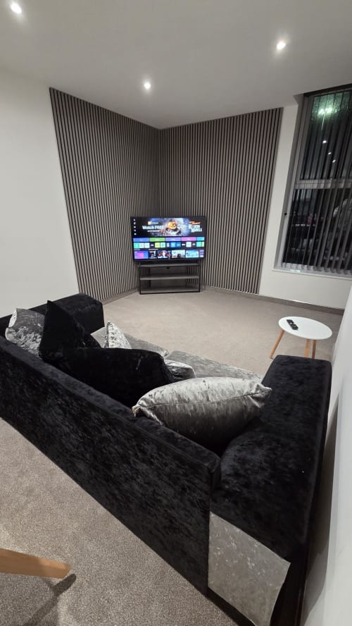 Modern home cinema at The Family Flat by JS Apartments, Blackburn, with black velvet sofa and striped accent wall