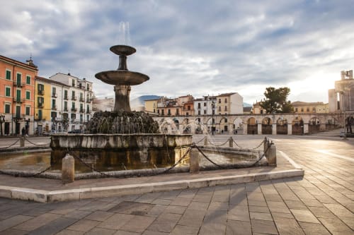 Fontana storica nella piazza centrale di Sulmona con edifici rinascimentali colorati e architettura ad archi