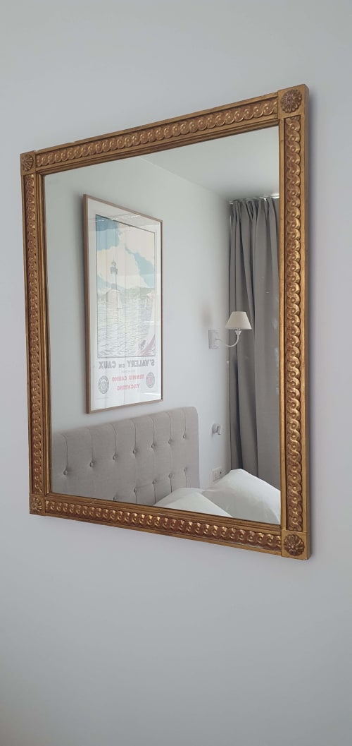 Miroir doré orné reflétant la chambre des Cabines à Houlgate, montrant la tête de lit rembourrée et les rideaux