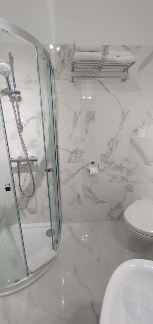 Salle de bains moderne aux murs en marbre, douche italienne avec paroi en verre courbe et toilettes aux Cabines de Houlgate