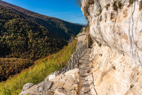 Sentiero di montagna con ringhiera in metallo con vista sulla valle boscosa presso Sulmona, Italia