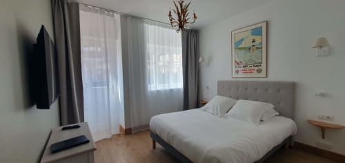 Chambre moderne à l'hôtel Les Cabines Houlgate avec lit double, TV écran plat, vue sur la ville et mobilier contemporain