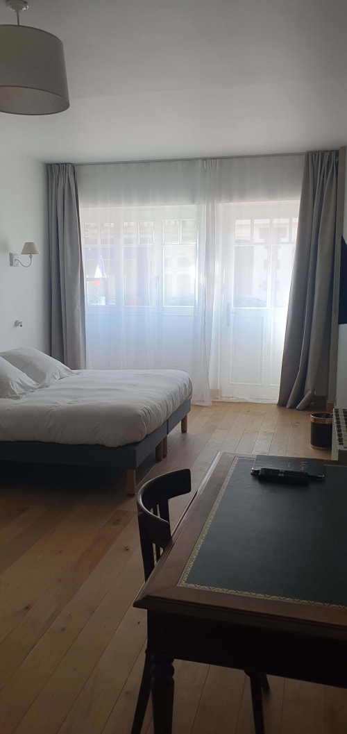 Chambre moderne aux Les Cabines, Houlgate avec lit, bureau et portes vitrées donnant sur la ville