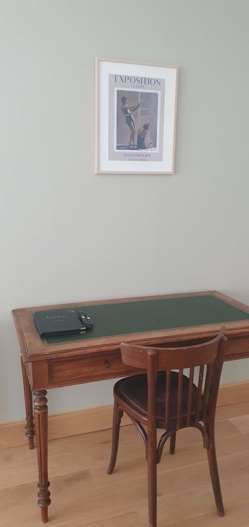 Bureau en bois avec plateau en cuir vert et chaise vintage à l'hôtel Les Cabines à Houlgate, affiche d'exposition sur le mur