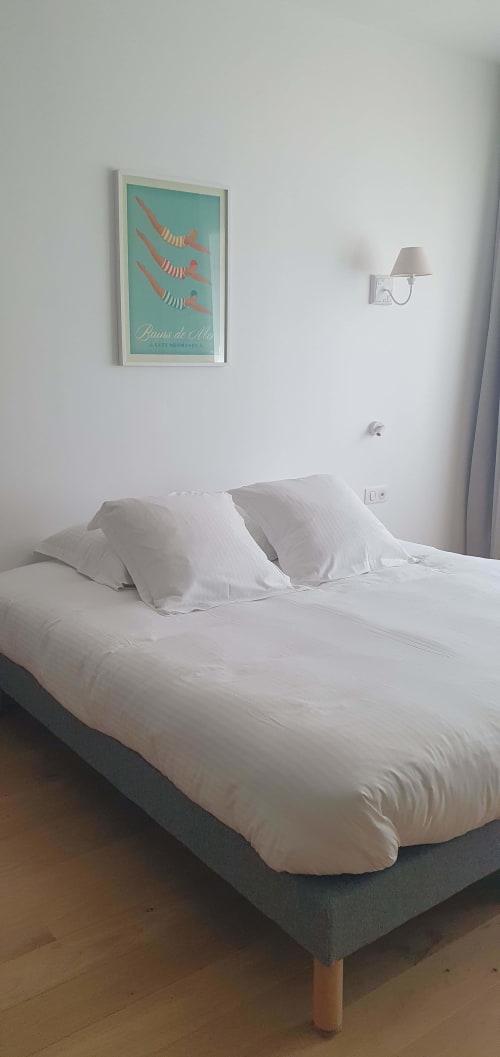 Chambre minimaliste aux Cabines à Houlgate avec oreillers blancs, décoration murale et lampe de chevet