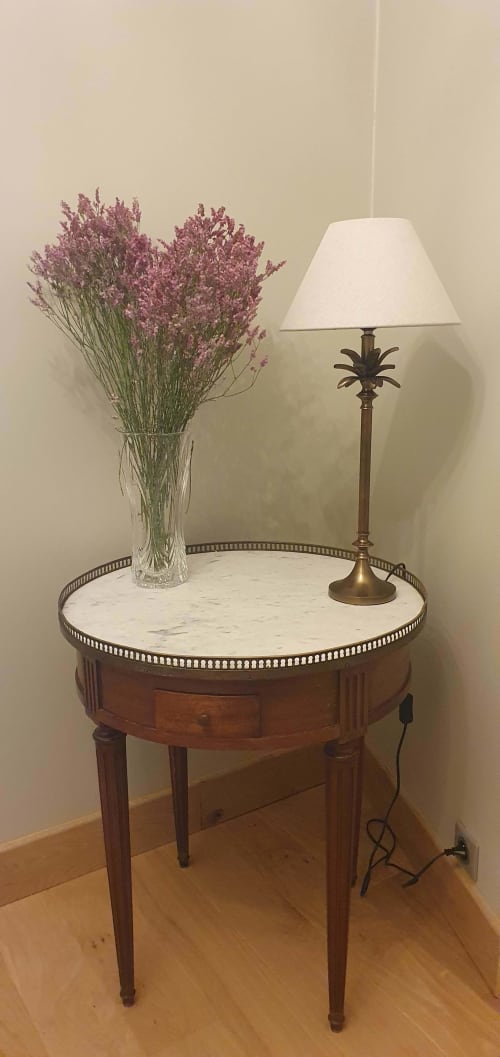 Table d'appoint ronde élégante au plateau en marbre, vase en verre avec fleurs séchées violettes et lampadaire en laiton dans la chambre de l'hôtel Les Cabines