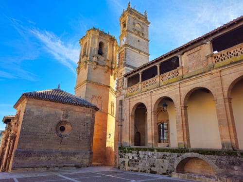 Historic church architecture in Alcaraz with bell towers and arched colonnade