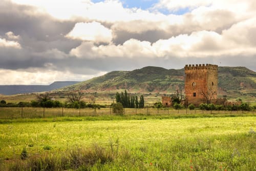 Historic tower in green valley landscape near Alcaraz, Spain with mountains and cloudy sky at Finca El Arroyo