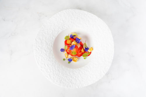 Elegant plated dish at Le S'Y Seingbouse featuring fresh strawberries, edible flowers, and colorful garnishes on white plate