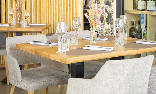 Elegant dining room at Hôtel Restaurant Le S'Y in Seingbouse with wooden table, upholstered chairs, wine glasses, and modern