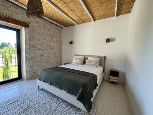Chambre moderne au Domaine Mas Lafleur avec murs en pierre, plafond bois et portes vitrées donnant sur terrasse à Châteaurenard