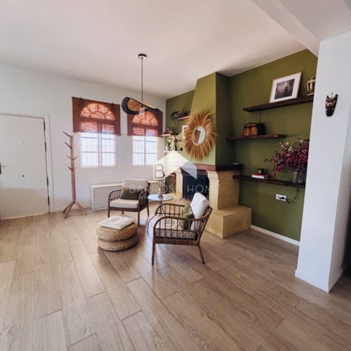Salón moderno de villa en Barrosa Home con pared acento verde oliva, suelo de madera, cómodos asientos y vista al jardín