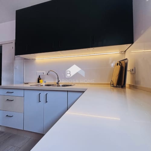 Cocina moderna en Villa Faro de Barrosa Home con encimeras blancas, armarios negros e iluminación ambiental