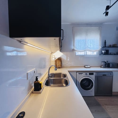 Cocina moderna en Villa Faro, Barrosa Home, Hozanejos, con fregadero de acero inoxidable, encimera blanca e integrada