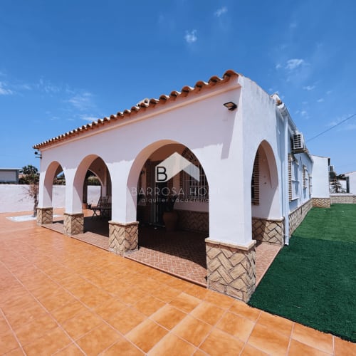 Villa Barrosa en Hozanejos con muros blancos, tejado de barro, entrada arqueada y jardín bien cuidado bajo cielo azul