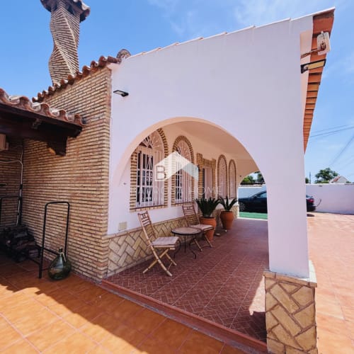 Villa Faro en Hozanejos con pérgola blanca, arco de ladrillo, sillas de mimbre y vistas al jardín privado