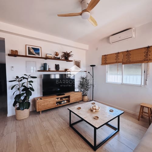Sala moderna de la villa Barrosa Home con mueble TV de madera, mesa de centro y vistas al jardín