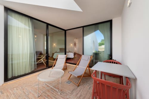 Modern studio apartment terrace at Monte das Açoteias with loungers, table, and views of the pool and countryside in Tavira,