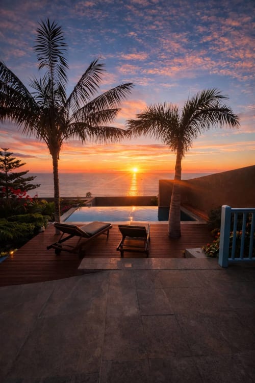 Vista del atardecer desde la terraza del hotel La Palma con palmeras, piscina infinita y tumbonas frente al océano