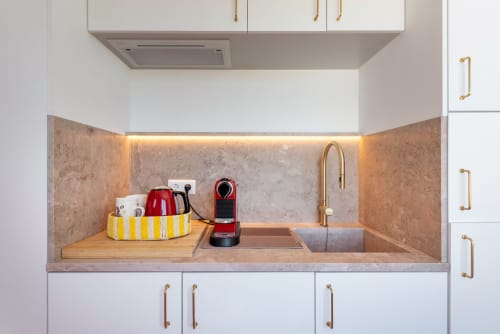 Modern kitchenette in Estúdio at Monte das Açoteias, Tavira with white cabinets, stone backsplash, and gold fixtures