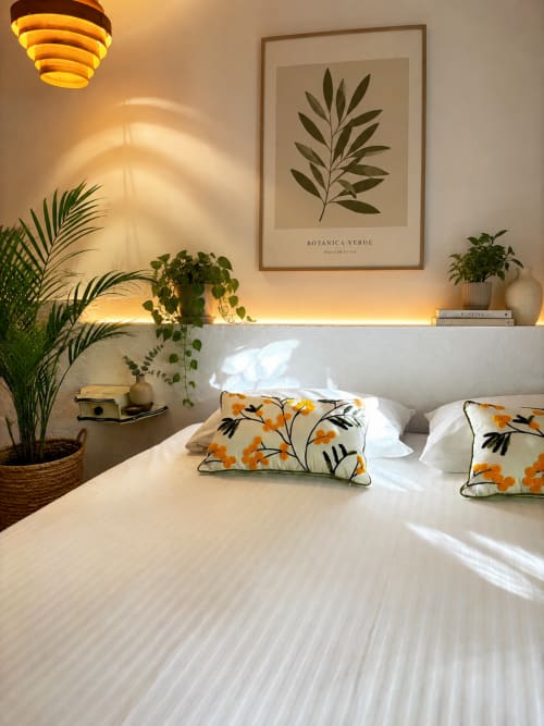 Habitació lluminosa a l'Hotel Mas Ribas a Palamós amb roba de llit blanca, coixins florals, plantes i vistes al jardí