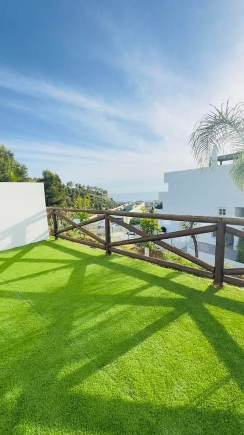 Amplia terraza con césped artificial, barandillas de madera y vistas panorámicas al mar en apartamento ALTOVELOO MAR en Torre de