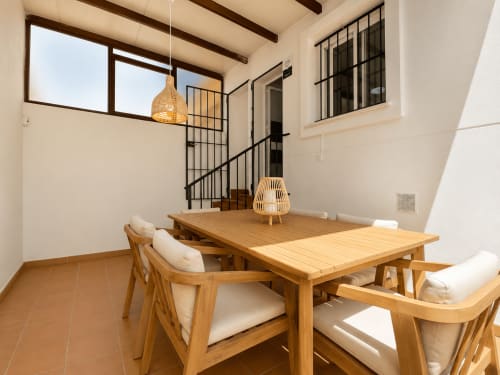 Comedor del apartamento Aroma de Poniente en Living Sur, Sanlúcar de Barrameda, con mesa de madera, sillas y lámpara colgante de tejido