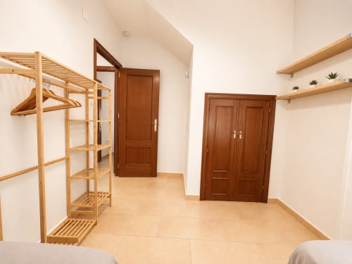 Dormitorio espacioso con armario de madera, estanterías y puertas dobles en el apartamento Aroma de Poniente, Sanlúcar de Barrameda