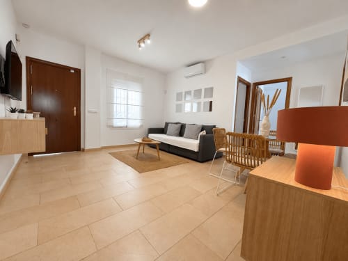 Salón moderno del apartamento Aroma de Poniente en Sanlúcar de Barrameda con sofá, mesa de comedor y zona de cocina