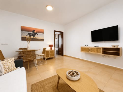 Sala de estar moderna con comedor, muebles de madera, TV empotrada y cuadro ecuestre en Living Sur, Sanlúcar