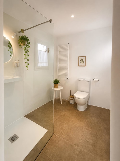 Bany modern a l'Hotel Mas Ribas de Palamós amb dutxa a ras de sòl, inodor, escalfador de tovalloles i decoració botànica