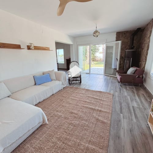 Amplio salón en Villa Irlanda de Barrosa Home, Chiclana, con sofás crema, estantes de madera y puertas correderas