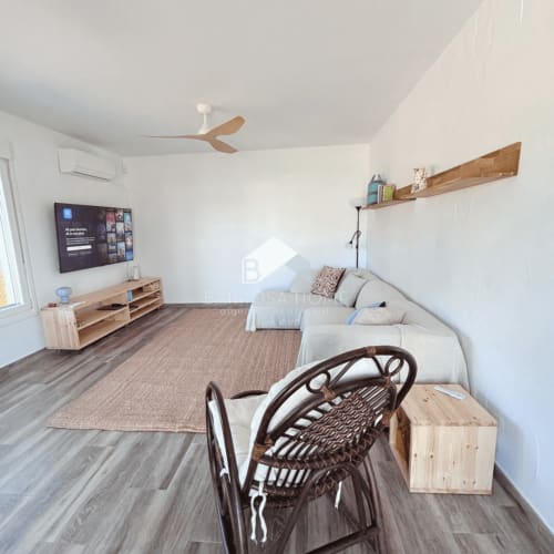 Sala de estar moderna en Barrosa Home, Chiclana de la Frontera, con sofá beige, televisor, muebles de madera y ventilador de techo