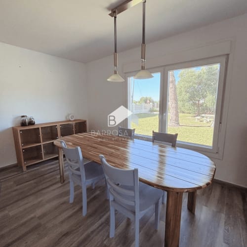 Comedor moderno con mesa de madera, sillas blancas y lámparas colgantes con vistas al jardín privado de Villa Irlanda, Chiclana