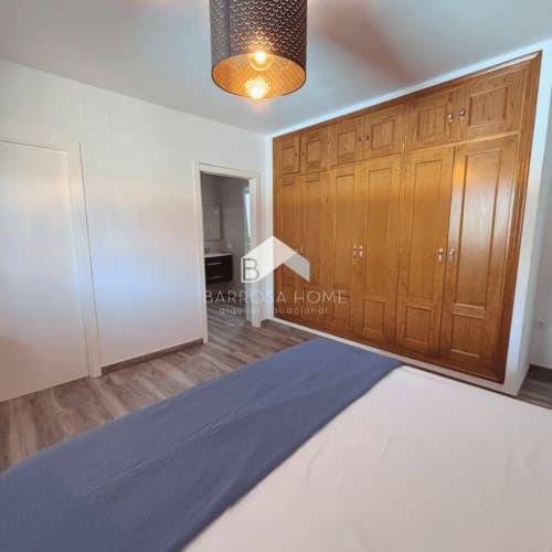 Amplio dormitorio en villa Barrosa Home en Chiclana con armarios de madera, cama y baño privado