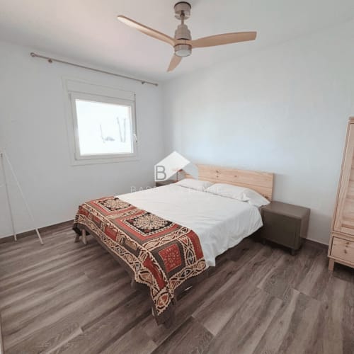 Dormitorio luminoso en la villa Barrosa Home de Chiclana con cama de madera, ventilador de techo y suelo de madera oscura