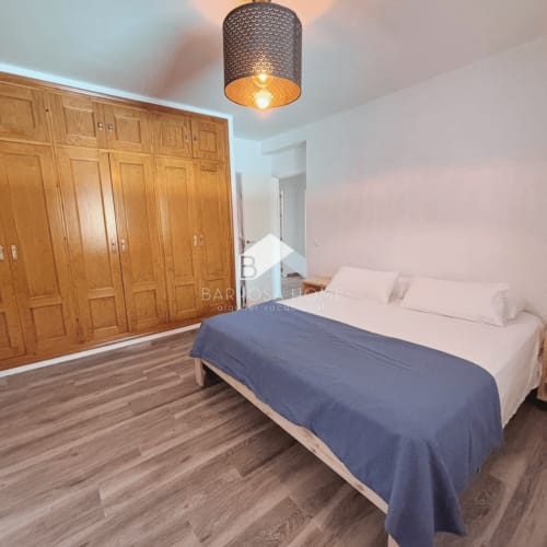 Amplia habitación en la villa Barrosa Home de Chiclana de la Frontera con armarios de madera, ropa de cama azul y techo moderno