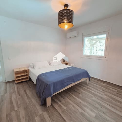 Dormitorio moderno en Villa Irlanda, Barrosa Home Chiclana con cama, mesita de noche de madera y ventana con vistas al jardín