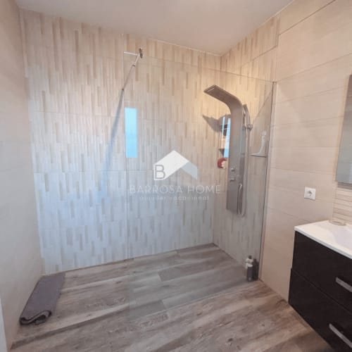 Baño moderno con ducha abierta, mampara de cristal y suelos de madera en la villa Barrosa Home de Chiclana de la Frontera