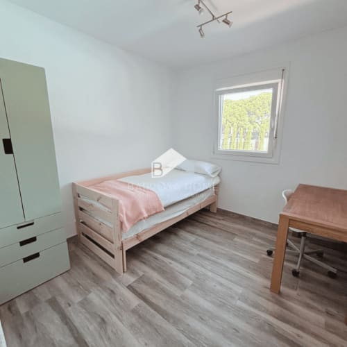 Dormitorio luminoso en villa Barrosa Home con cama individual, escritorio de madera, armario verde y vistas al jardín