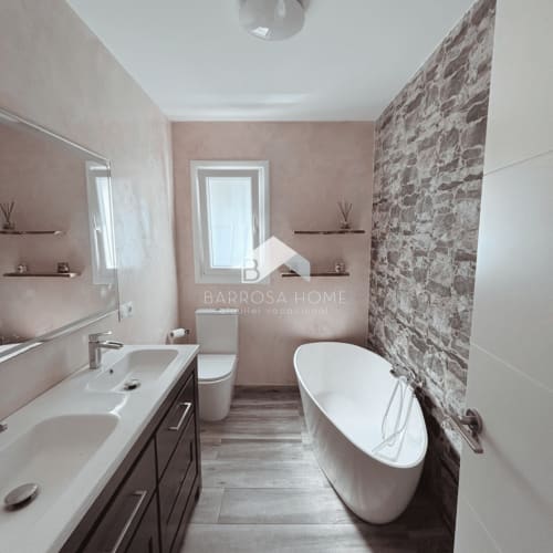 Moderno baño en villa Barrosa Home con bañera independiente, doble tocador y pared de ladrillo visto