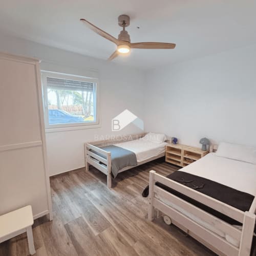 Luminoso dormitorio infantil en Villa Irlanda, Chiclana de la Frontera, con dos camas individuales, ventilador de madera y vista a la piscina