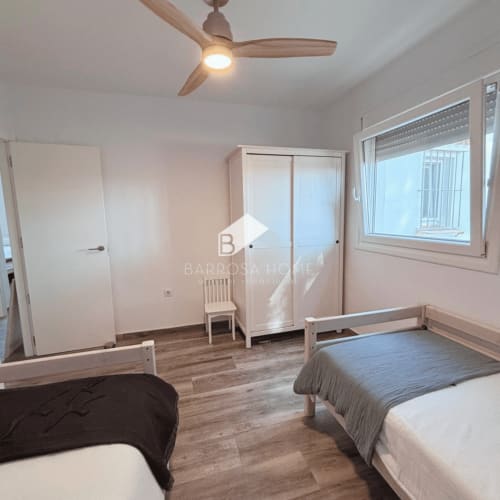 Habitación luminosa con dos camas individuales, ventilador de techo y armario en Villa Irlanda, Chiclana de la Frontera