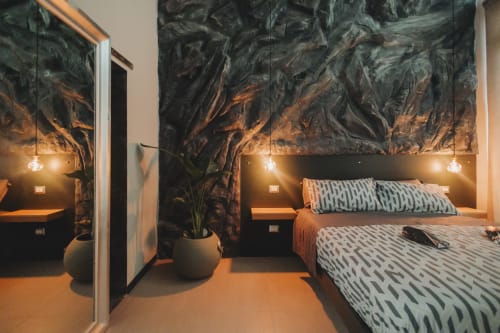Letto matrimoniale moderno nella Camera Esclusiva 101 di Oltre, Palermo, con pareti in marmo scuro, lampade a sospensione e vista sulla città