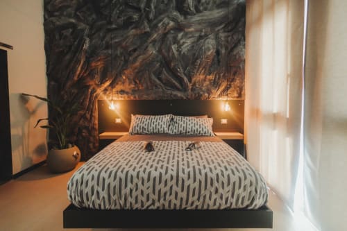 Letto matrimoniale moderno con biancheria fantasia nella suite deluxe Oltre Exclusive di Palermo, con testata artistica scura